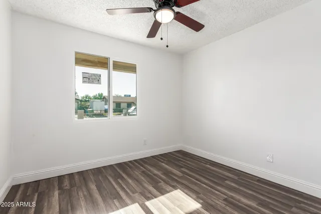 an empty room with wooden floor cabinet and windows