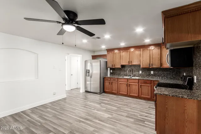 a kitchen with stainless steel appliances granite countertop a refrigerator a sink dishwasher a stove and a microwave oven with wooden floor