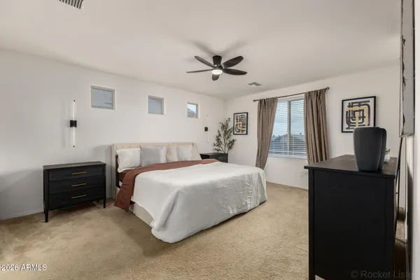 a spacious bedroom with a bed and dresser with mirror