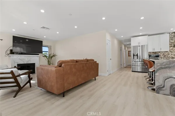 a living room with furniture a flat screen tv and kitchen view