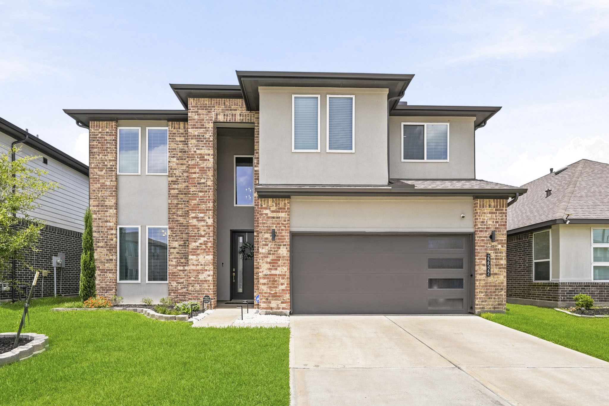 22522 Modica Rift Lane Katy, TX 77449 - Photo 4 of 38 From the moment you arrive, this home makes a statement. A striking two-story modern prairie façade blends warm multi-tone brick, crisp stucco panels, and bold dark trim into a look that's both timeless and distinctly contemporary. The sleek charcoal garage door with frosted panel accents, lush green lawn, and thoughtfully landscaped entry all signal that something special awaits inside.