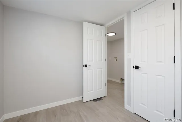 an empty room with wooden floor and entrance