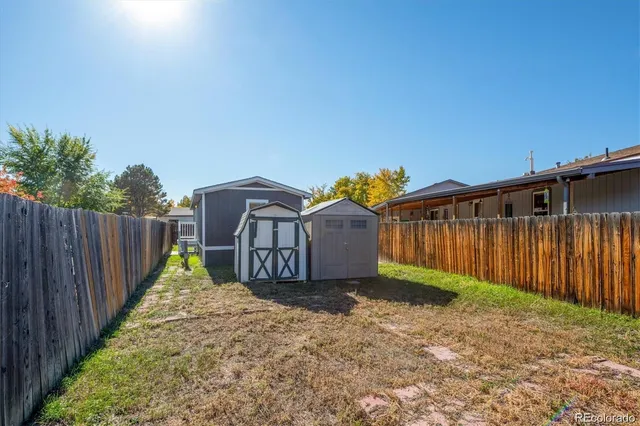 a view of a small house with wooden fence