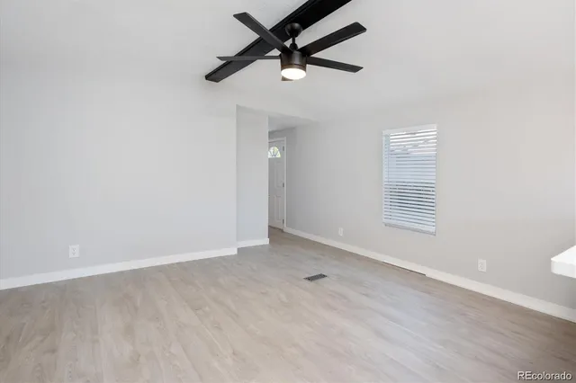 an empty room with a window and ceiling fan