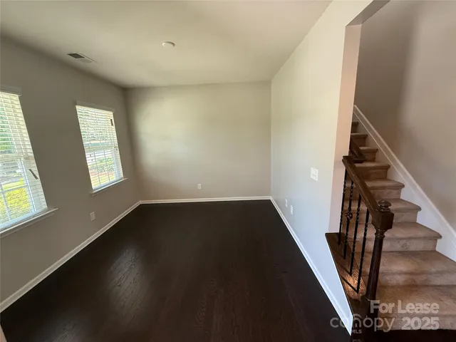 a view of an empty room with wooden floor and stairs