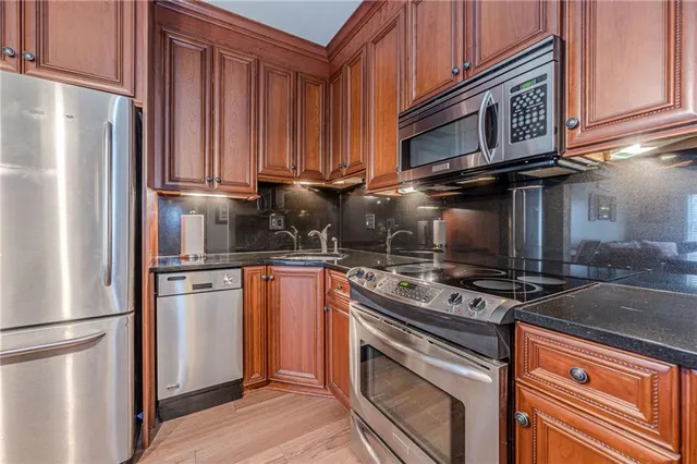 a kitchen with stainless steel appliances granite countertop a refrigerator and a stove top oven