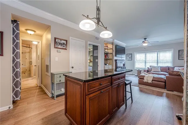 a kitchen with stainless steel appliances kitchen island granite countertop a stove a sink and a refrigerator with wooden floor