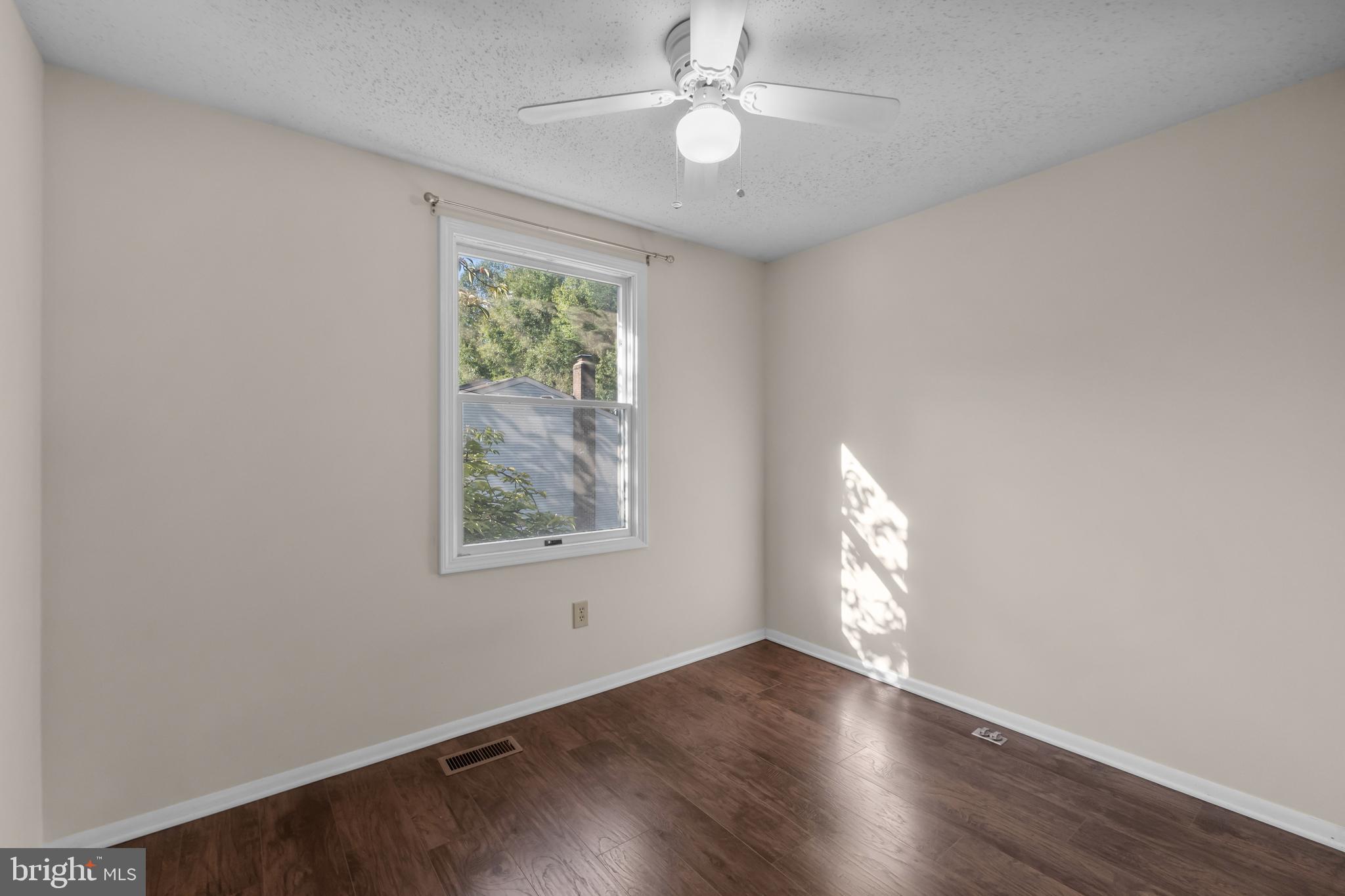 6832 Heatherway Court Alexandria, VA 22315 - Photo 15 of 37 an empty room with wooden floor chandelier fan and windows
