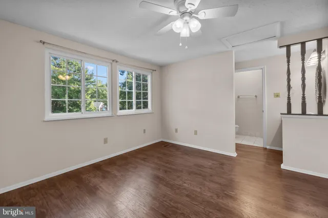 an empty room with wooden floor fan and windows