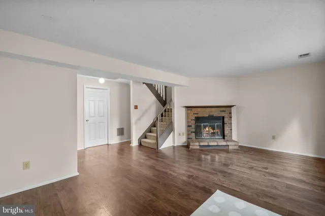 a view of an empty room with wooden floor fire place