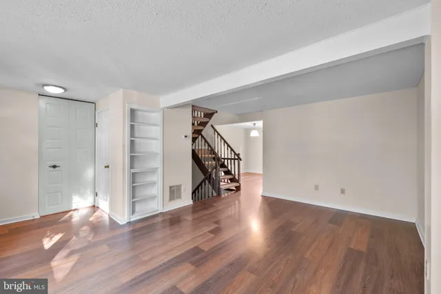 a view of empty room with wooden floor and stairs