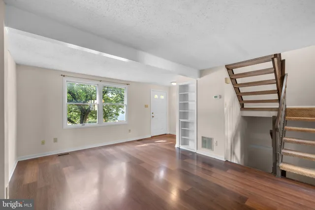 an empty room with wooden floor closet and windows