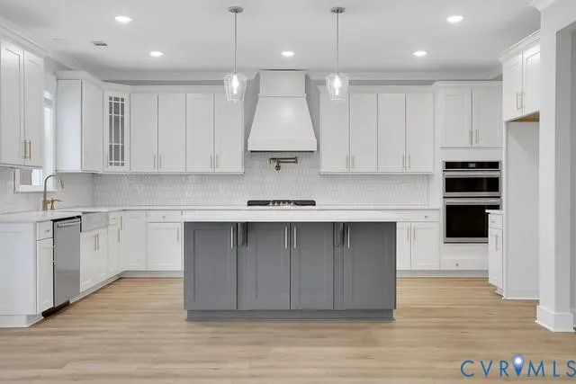 a kitchen with kitchen island granite countertop a stove a sink a refrigerator and white cabinets