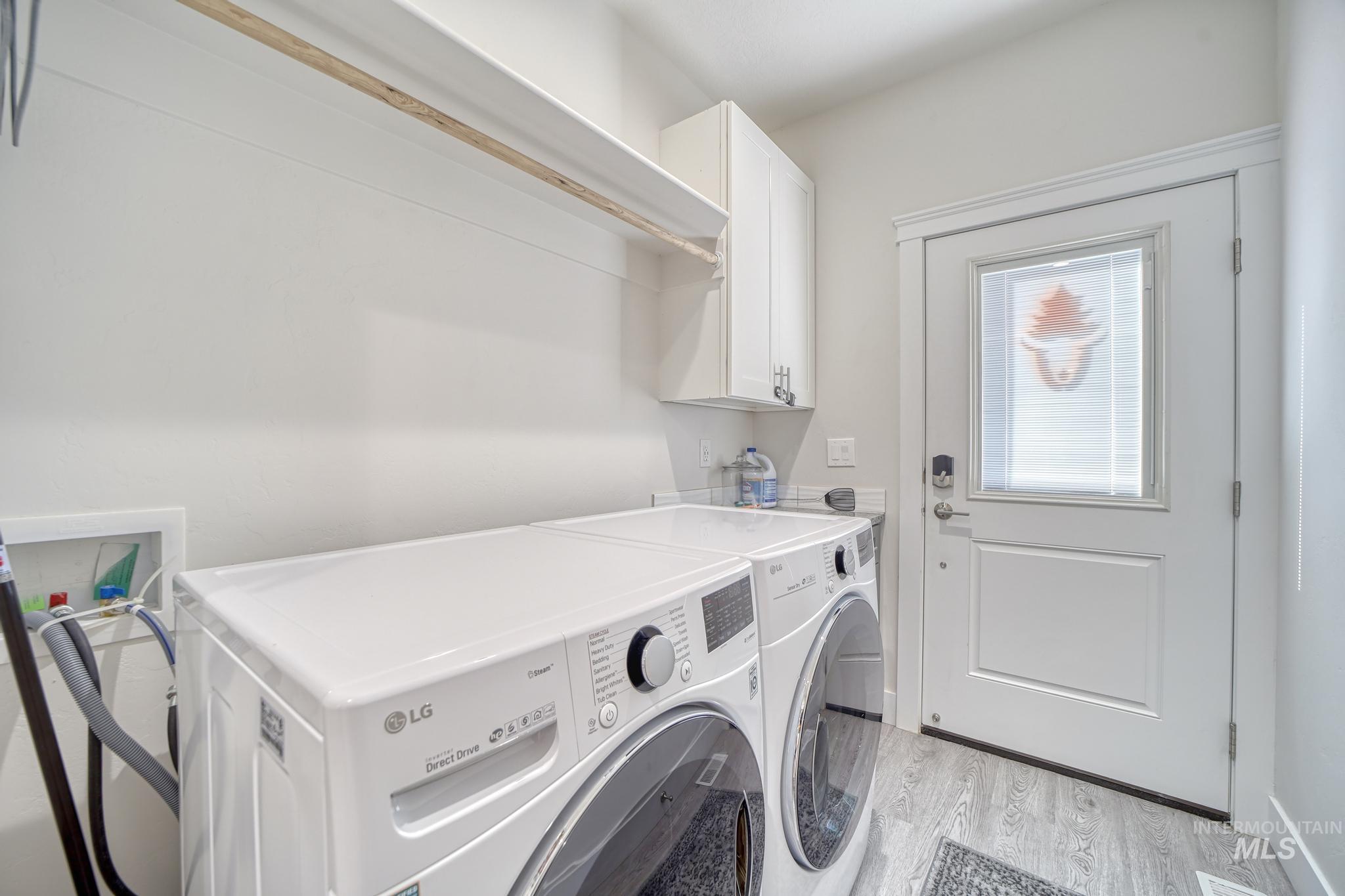 1087 Easy Avenue Twin Falls, ID 83301 - Photo 19 of 25 Laundry area with light wood-style flooring, washing machine and clothes dryer, and cabinet space