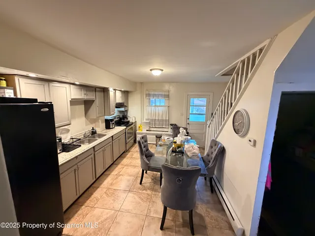 a kitchen with stainless steel appliances granite countertop a refrigerator a stove a sink a dining table and chairs with wooden floor