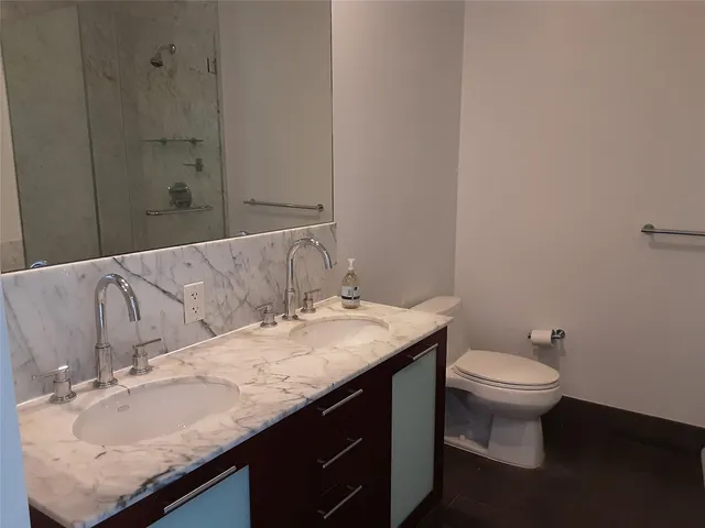 a bathroom with a granite countertop sink and a toilet