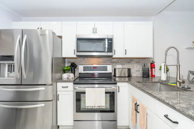 a kitchen with granite countertop a refrigerator stove and microwave