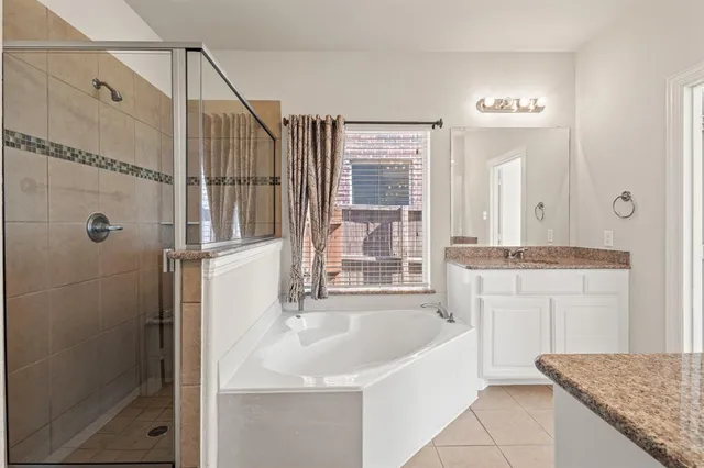 a bathroom with a granite countertop sink a mirror and a bathtub
