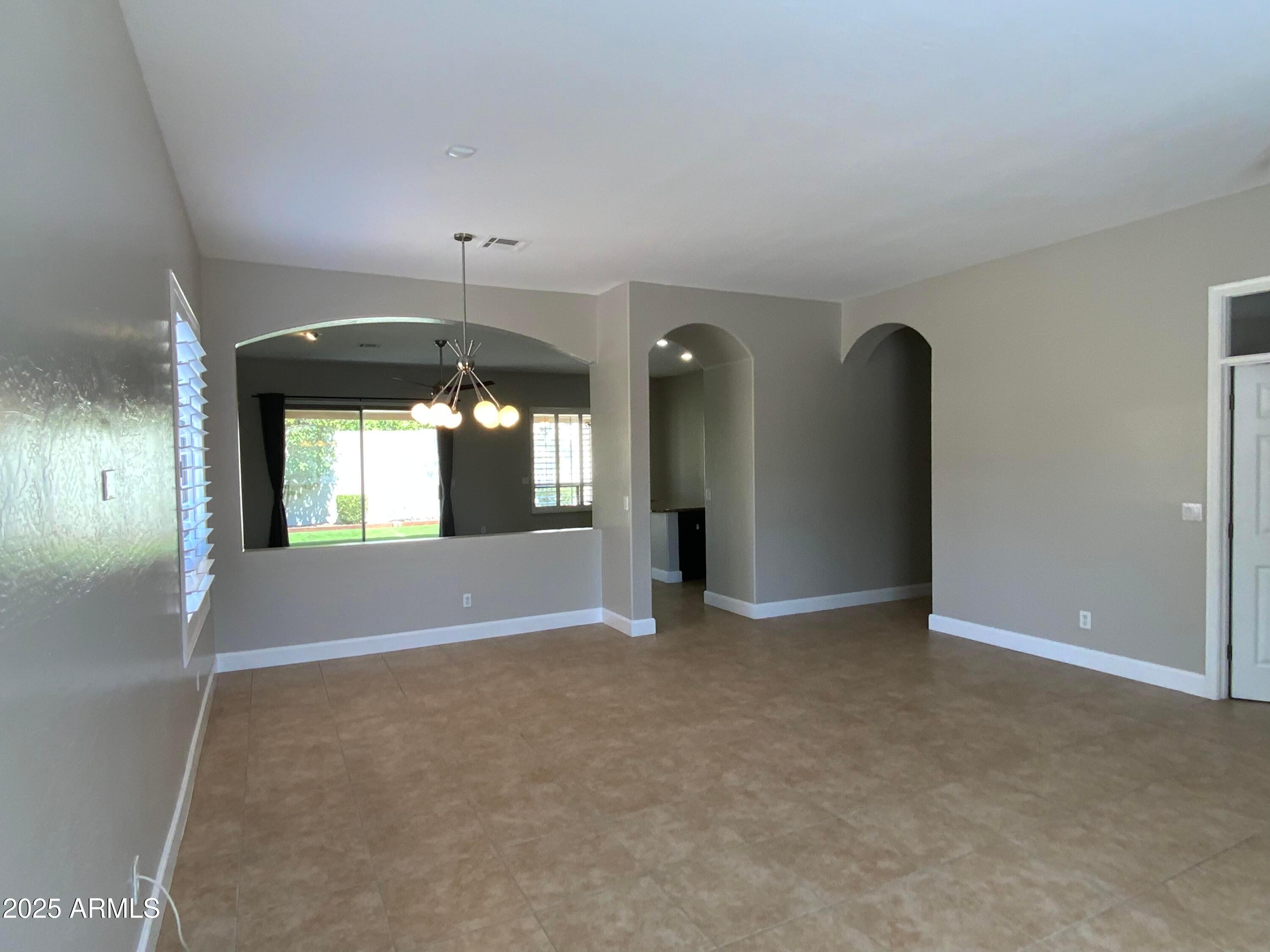 6204 East Phelps Road Scottsdale, AZ 85254 - Photo 12 of 25 an empty room with chandelier fan and windows