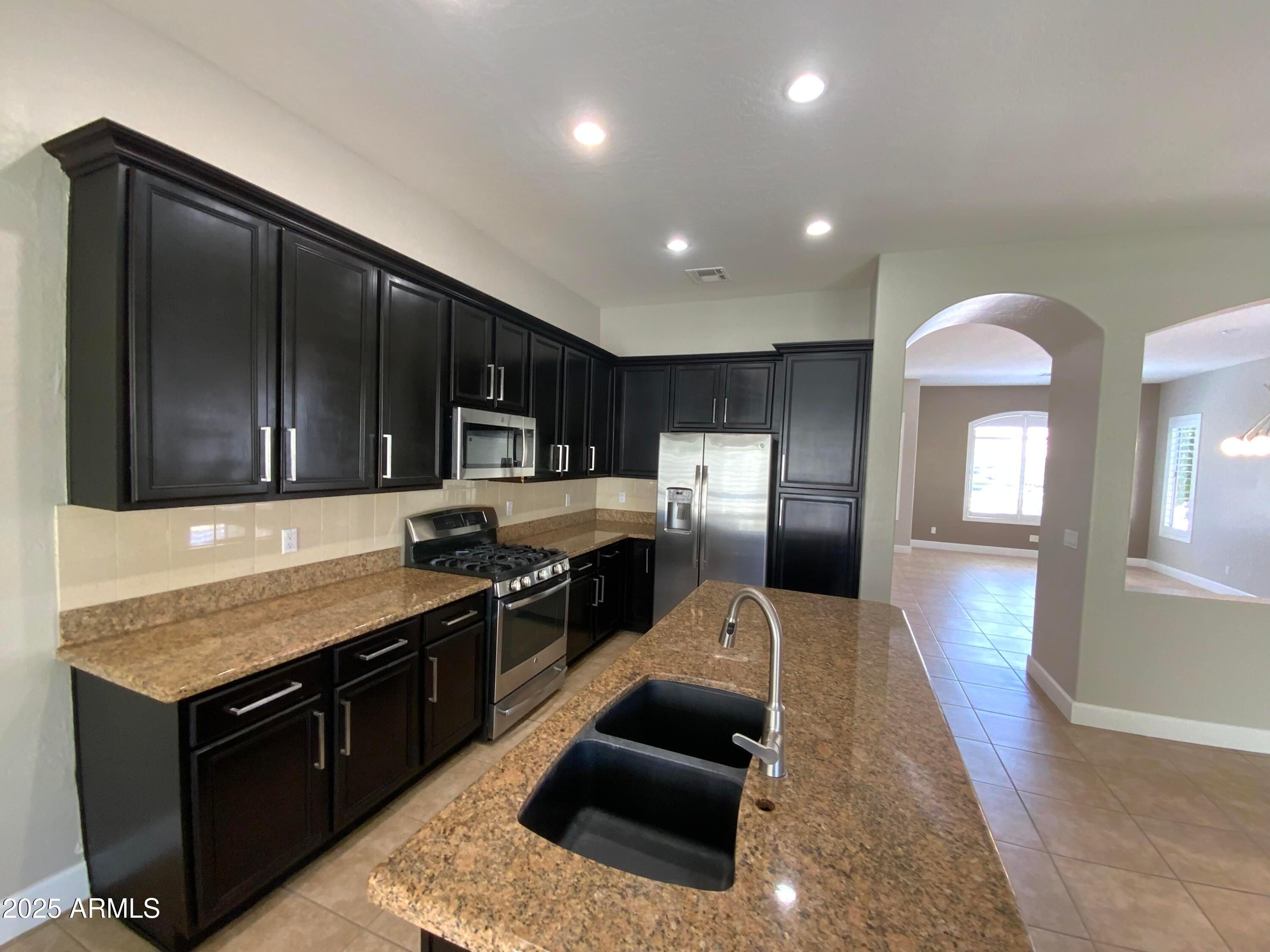 6204 East Phelps Road Scottsdale, AZ 85254 - Photo 10 of 25 a kitchen with stainless steel appliances granite countertop a sink stove and refrigerator