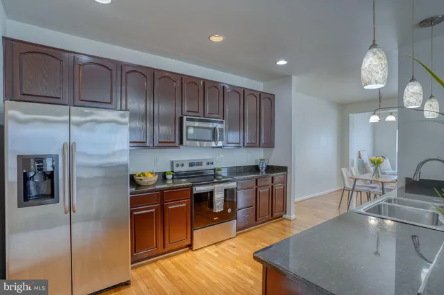 a kitchen with stainless steel appliances granite countertop a sink a stove and a refrigerator