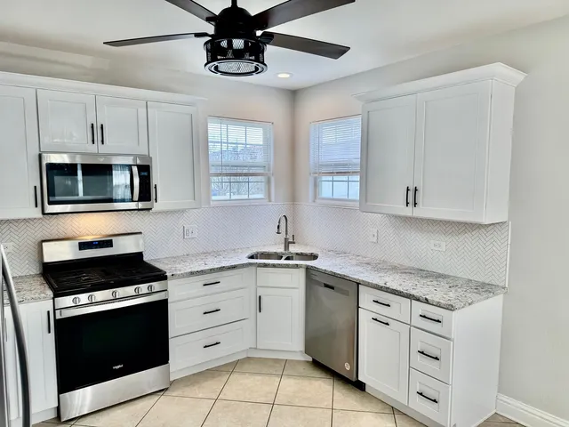 a kitchen with white cabinets stainless steel appliances and a window