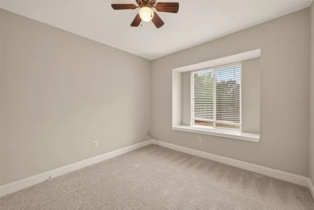 an empty room with a window and a fan