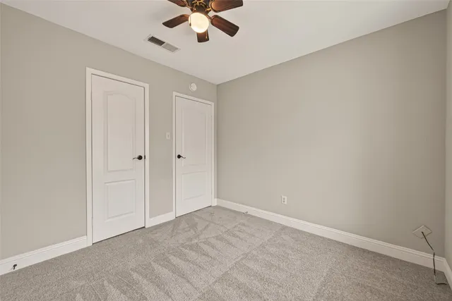 an empty room with a chandelier fan and a ceiling fan