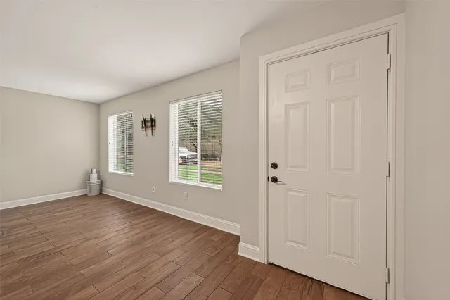 an empty room with wooden floor and windows