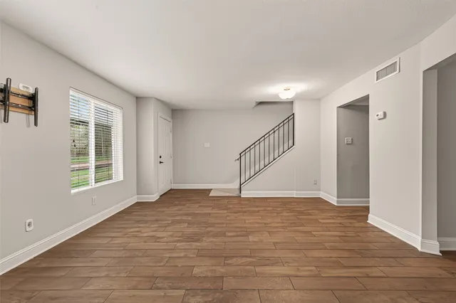 a view of an empty room with wooden floor and a window