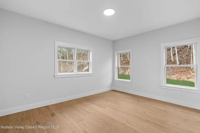 a view of an empty room with a window and wooden floor