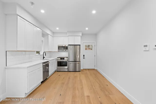 a kitchen with stainless steel appliances a refrigerator sink and white cabinets