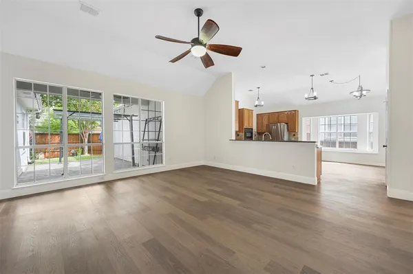 a view of empty room with wooden floor and fan