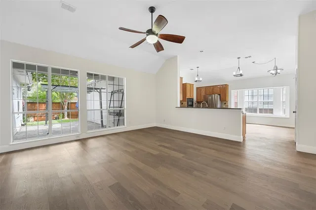 a view of empty room with wooden floor and fan