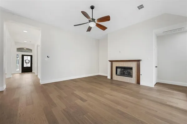 a view of an empty room with window and wooden floor
