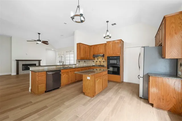 a large kitchen with stainless steel appliances granite countertop a lot of cabinets and wooden floor