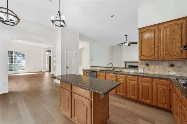 a kitchen with granite countertop a sink cabinets and wooden floor