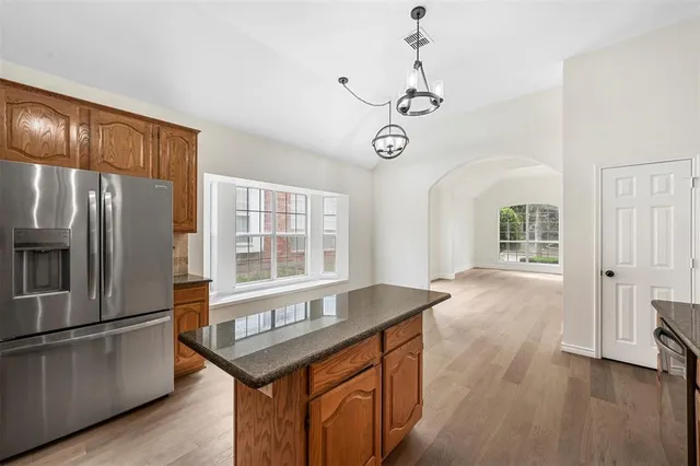 a kitchen with stainless steel appliances granite countertop a refrigerator a stove and a refrigerator with wooden floor