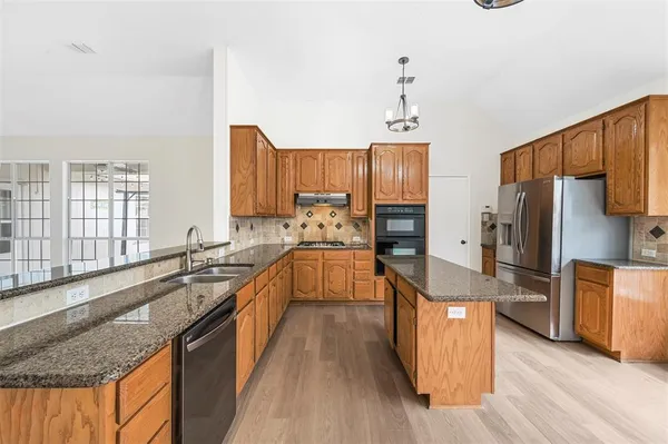 a kitchen with stainless steel appliances granite countertop a stove refrigerator and cabinets