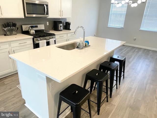 8804 Woodyard Station Road Clinton, MD 20735 - Photo 10 of 39 a kitchen with stainless steel appliances white cabinets and wooden floor
