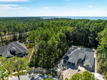 an aerial view of residential house with outdoor space and trees in the background