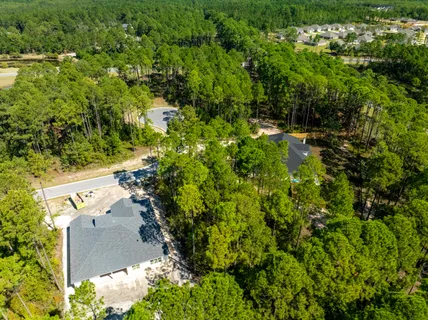 an aerial view of residential house with outdoor space and trees all around