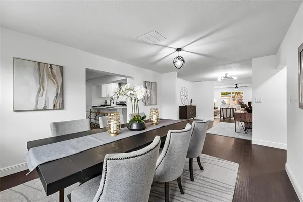 a dining room with wooden floor and a kitchen
