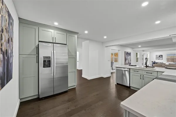 a kitchen with stainless steel appliances a refrigerator sink and wooden floor