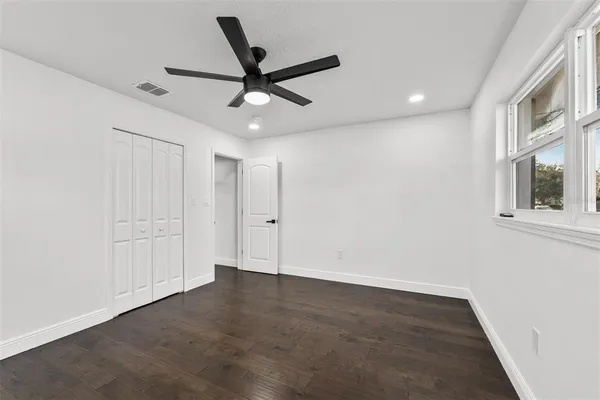 an empty room with ceiling fan and windows
