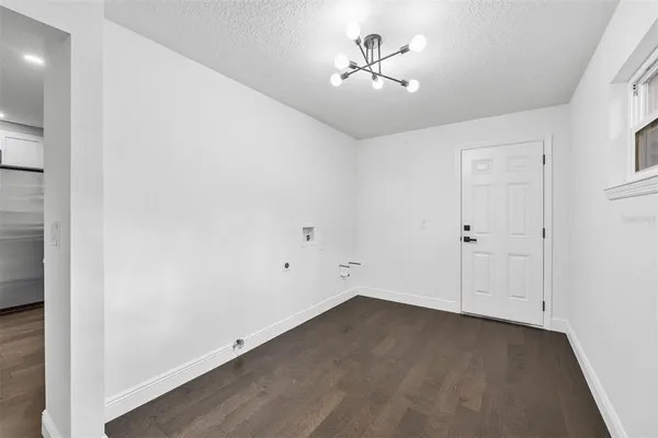 an empty room with a chandelier fan and wooden floor