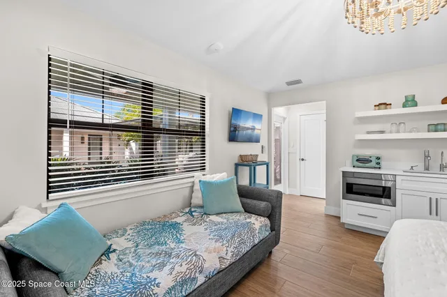 a bedroom with a bed and dresser with wooden floor