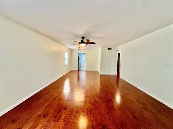 a view of a livingroom with wooden floor ceiling fan and window