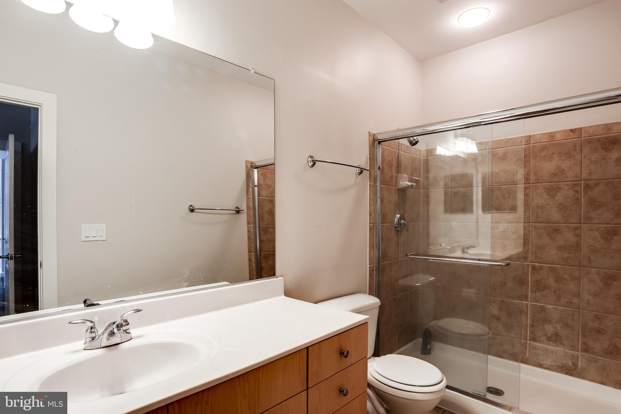 2007 Clipper Park Road, Unit 124 Baltimore, MD 21211 - Photo 19 of 35 a bathroom with a sink a toilet a mirror and shower