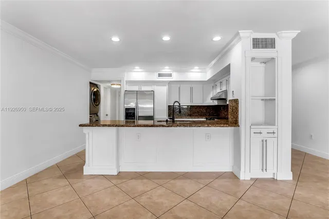 a living room with stainless steel appliances kitchen island granite countertop a refrigerator and a sink